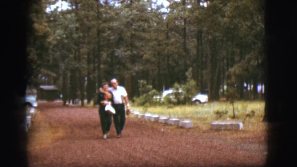 Near the end of the 1968 Flagstaff clip, the couple walks closely on the wooded dirt path with vintage cars in the background.