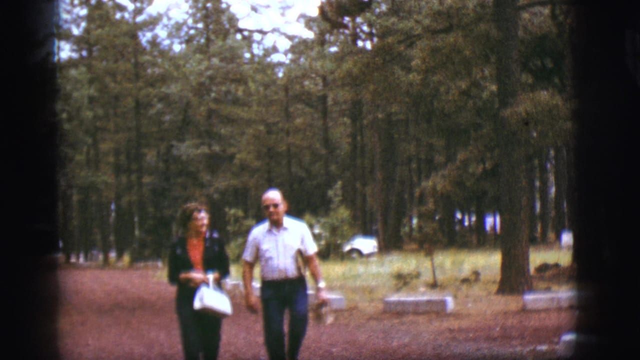 Older couple walking side by side through a wooded area.