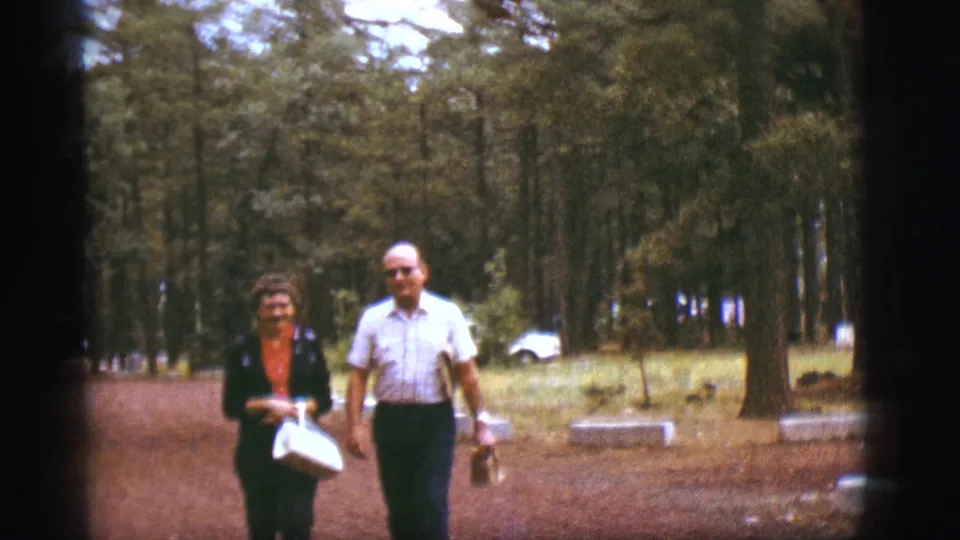 In the 1968 Flagstaff home-movie frame, the couple nears the camera while walking through a wooded area.