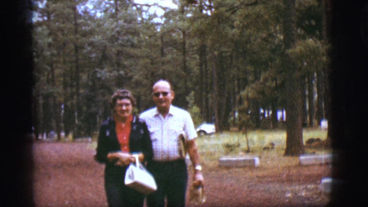 Adult couple walking toward the camera on a pine forest dirt path.