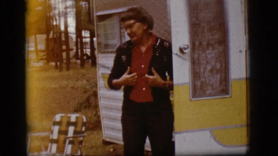 In the final 1968 Flagstaff frame, the woman with glasses faces outward beside the trailer, with chair, trees, and warm film fading visible.