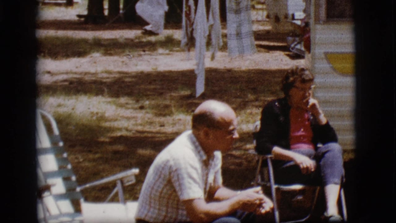 A man and woman sit in folding chairs outside a white and yellow trailer in Flagstaff, Arizona, in 1968 home-movie footage.
