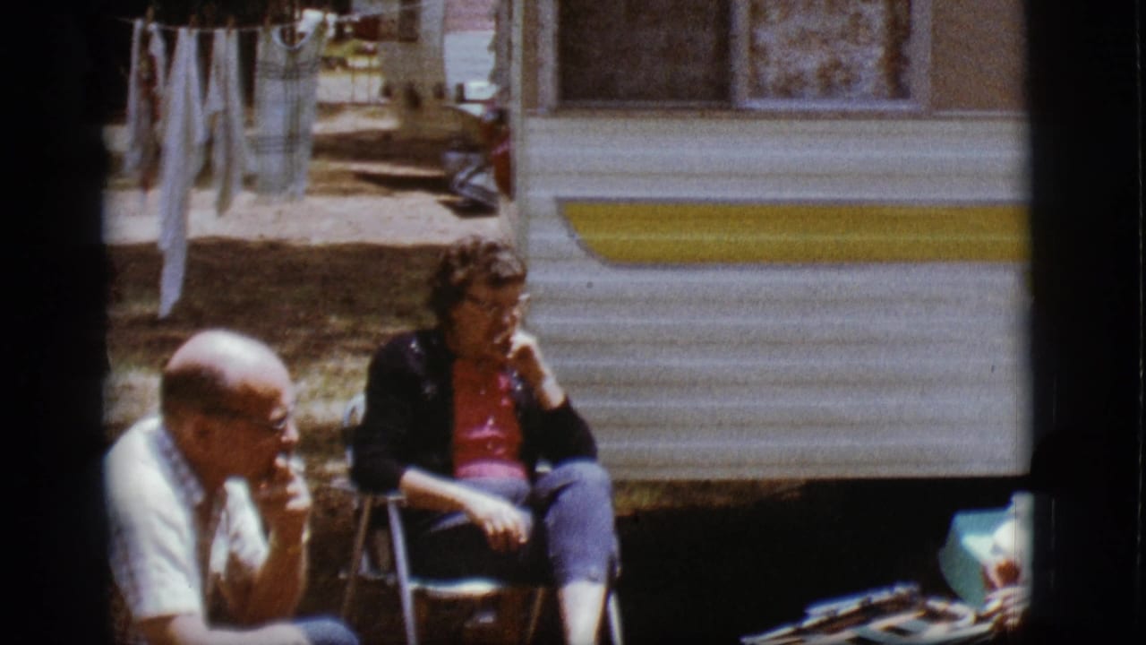 A seated man and woman appear outside a white and yellow trailer in the 1968 Flagstaff home-movie scene.