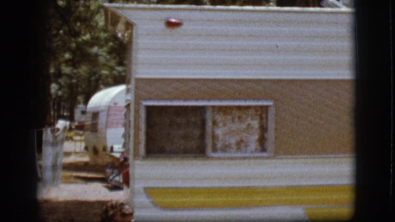 A white and yellow camper fills the frame with laundry and another trailer in the background.