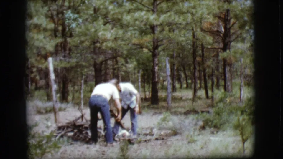 The men continue gathering and arranging dry sticks on the forest floor in 1968 Flagstaff home-movie footage.