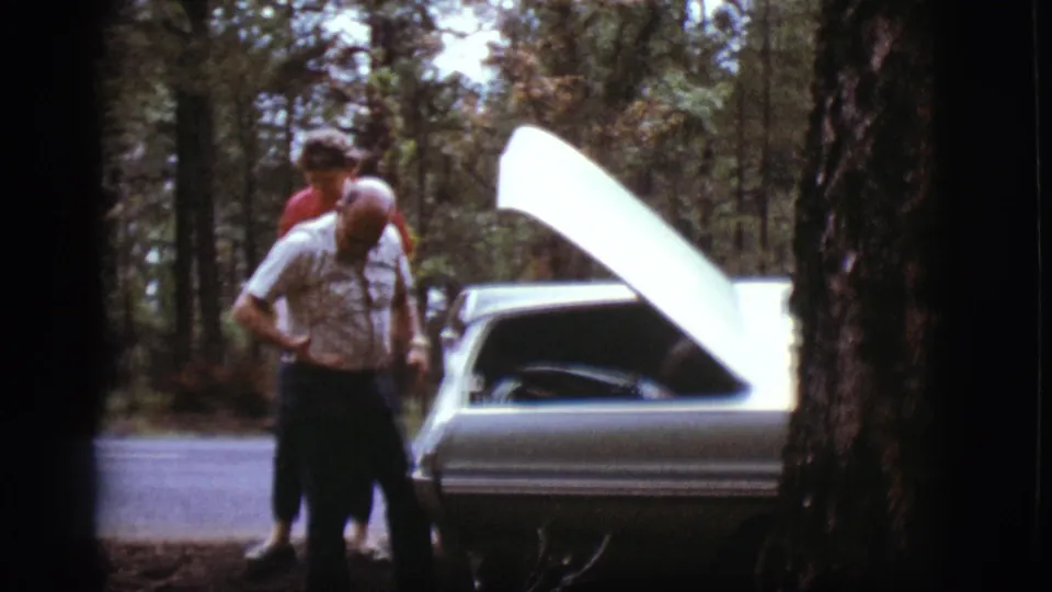 The man steps back from the open engine area, suggesting the check is ending, with the woman partly hidden behind him.