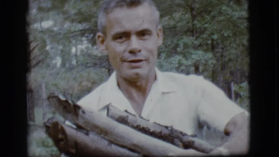 Close-up from the 1968 Flagstaff clip shows the man holding a bundle of wood against a forest background.