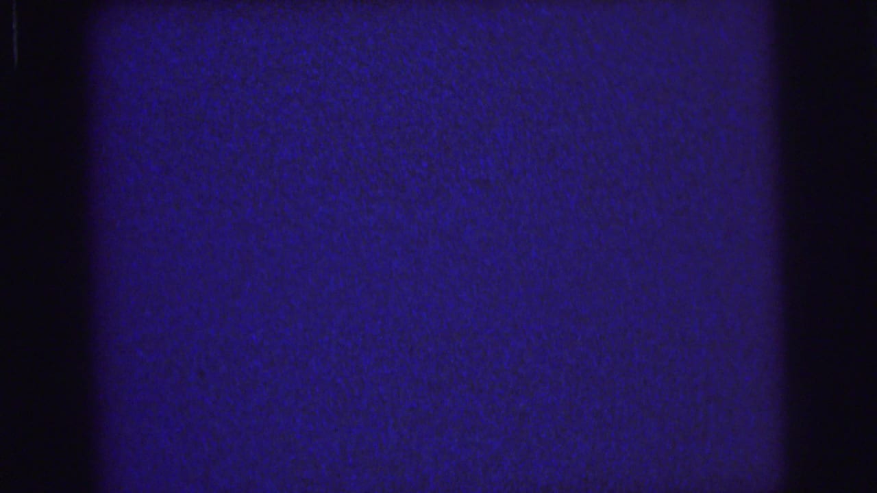 Blue grainy film field with dark vertical bands and faint horizontal line.