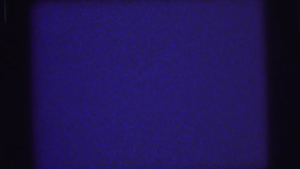 1976 Lynbrook 8mm frame showing a blue, grainy blank field with black vertical frame-edge bands and faint surface marks.