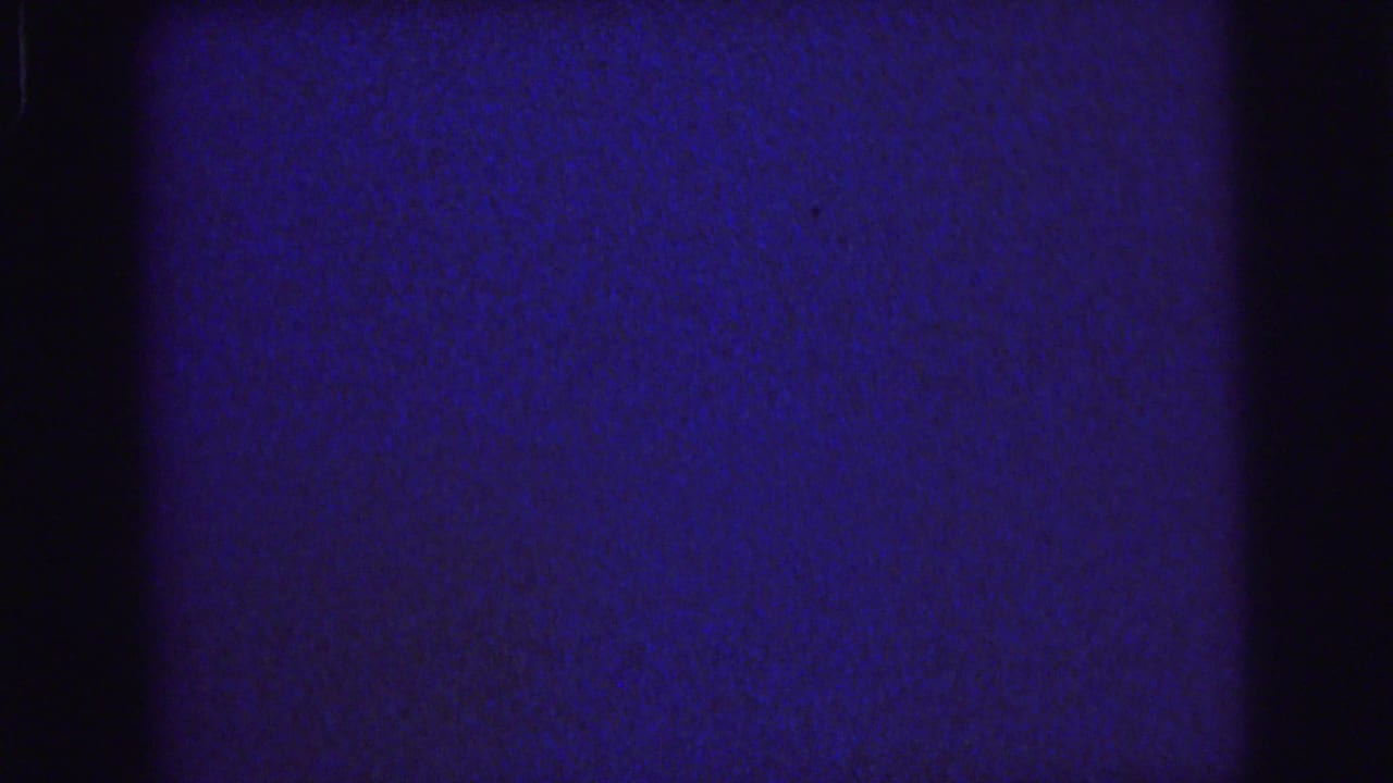 1976 Lynbrook 8mm frame with blue film density, a broad black vertical band, grain, and minor scratches.