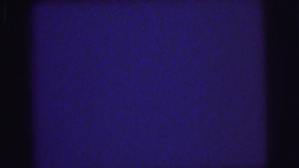 1976 Lynbrook 8mm frame with blue static-like grain, black vertical bands, and small dust or scratch marks.