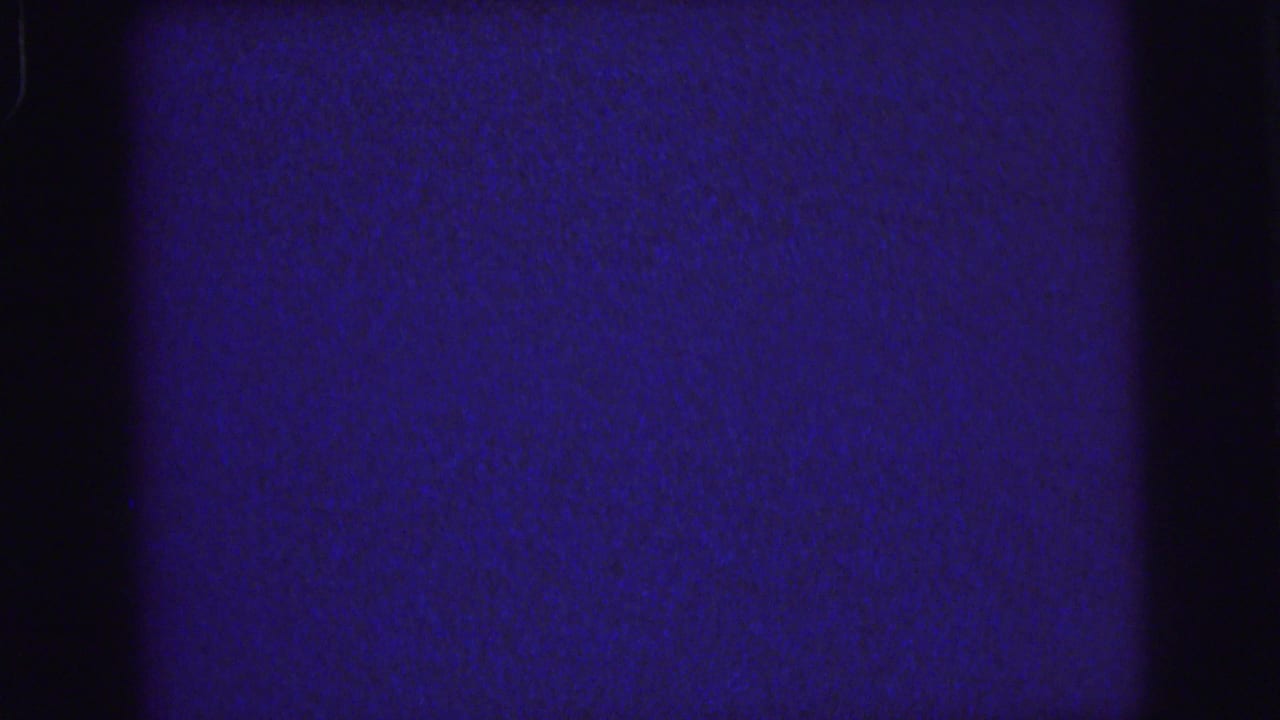 Dark blue grainy film frame with black vertical edge shadows and faint surface marks.