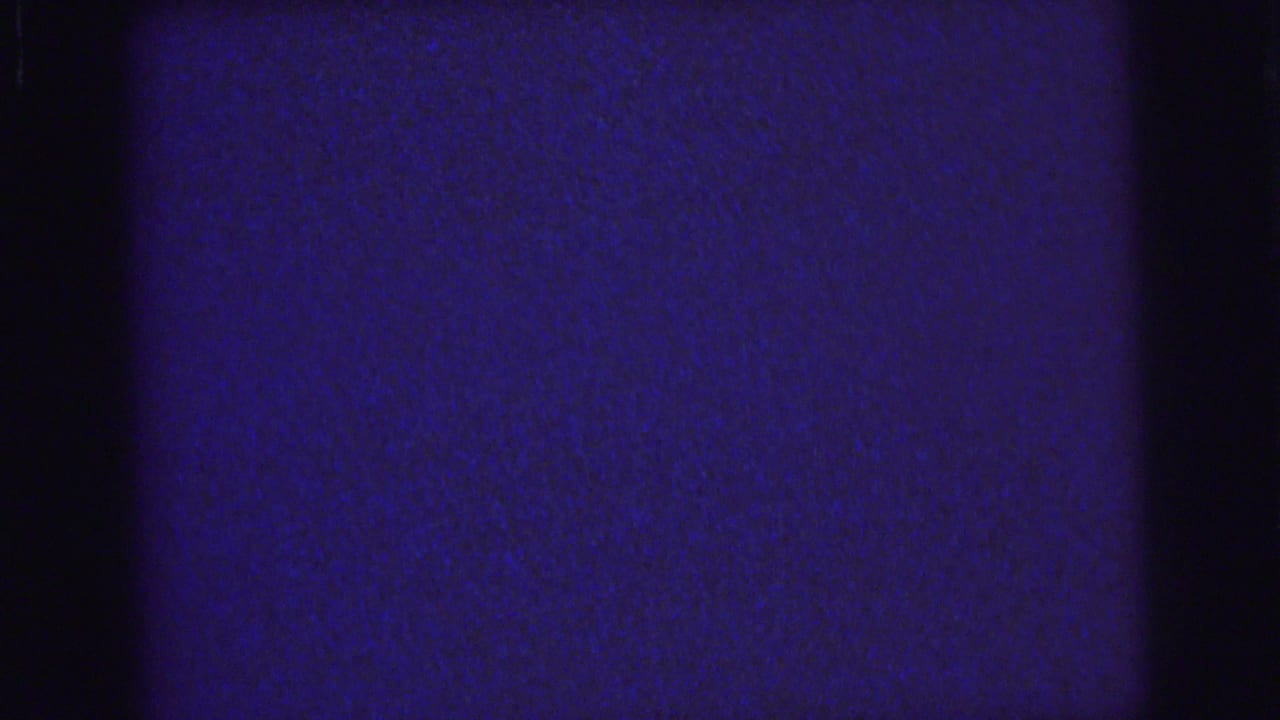 1976 Lynbrook 8mm frame with deep blue grain, dark vertical bands, and subtle surface wear from the scanned film.