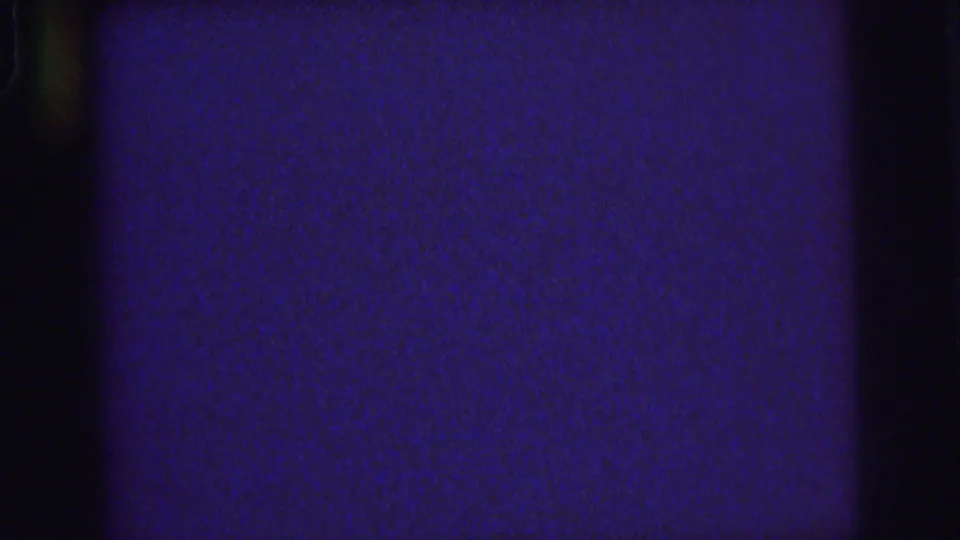 Abstract 1976 8mm frame from Lynbrook metadata showing deep blue-purple exposure, dark borders, and film grain.
