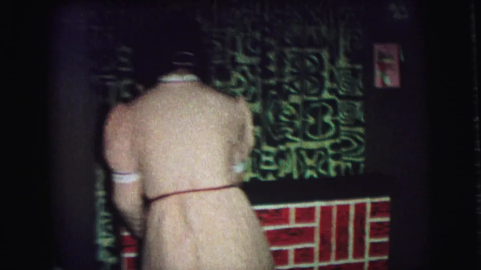 Woman in a pink robe faces the mantel area, with a holiday stocking and patterned decor visible in the Lynbrook home interior.