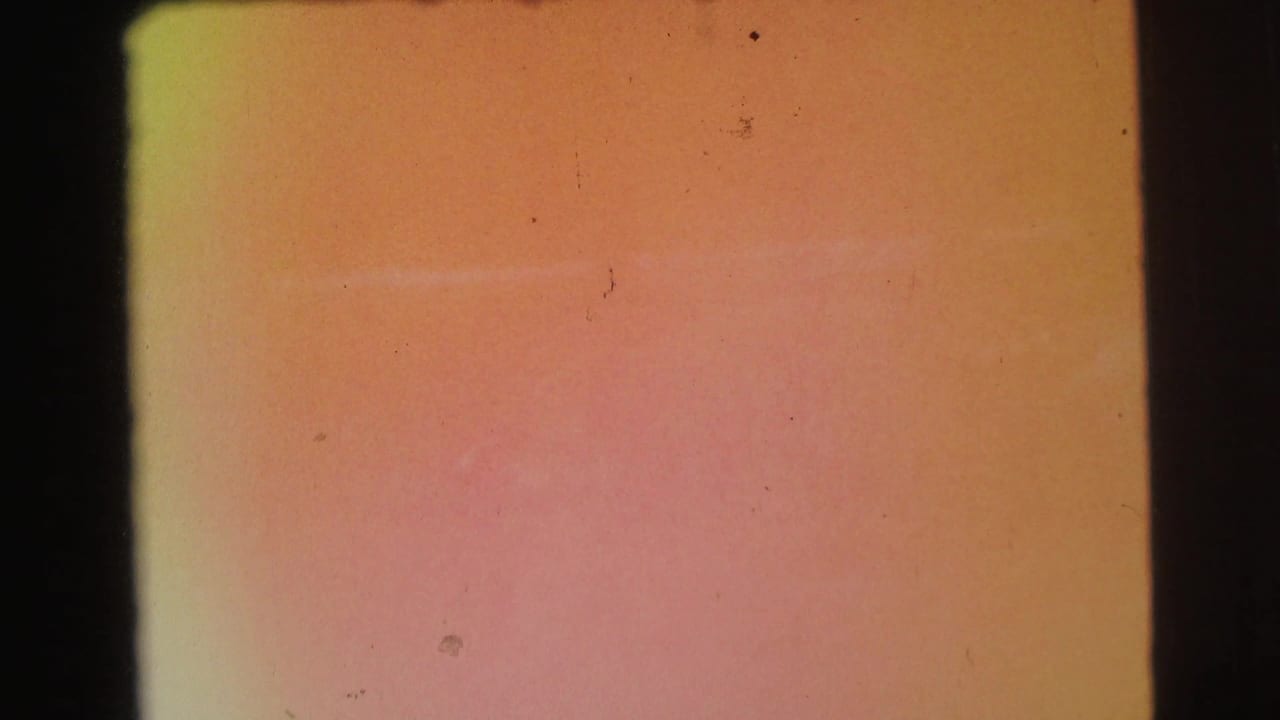 Orange-pink 8mm leader frame with faded color, dust specks, and a dark vertical film edge from the 1971 home-movie scan.