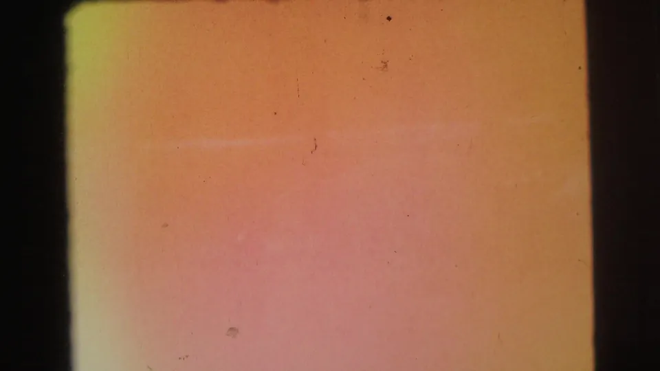 Orange-pink 8mm leader frame with faded color, dust specks, and a dark vertical film edge from the 1971 home-movie scan.