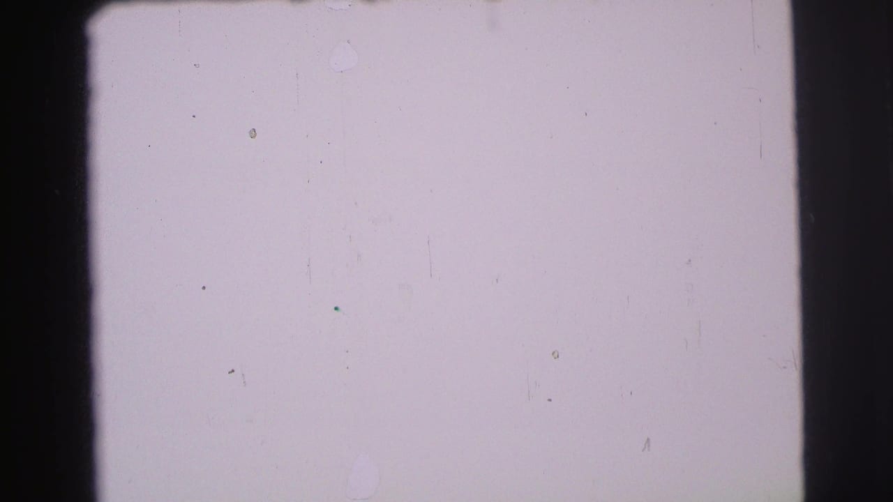Nearly blank pale frame with black film borders, dust, and scratches.