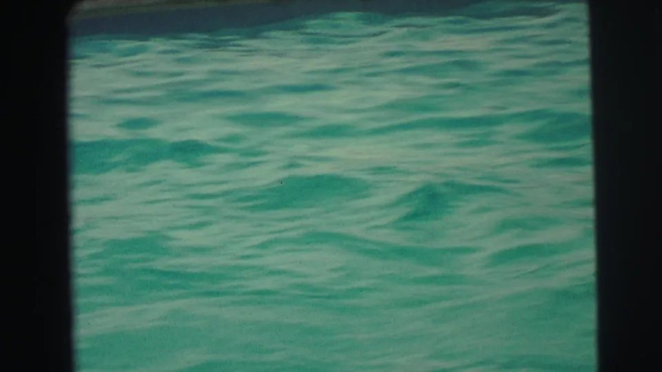 1971 Yellowstone, Wyoming home-movie frame showing only rippled turquoise pool water within dark 8mm scan borders.