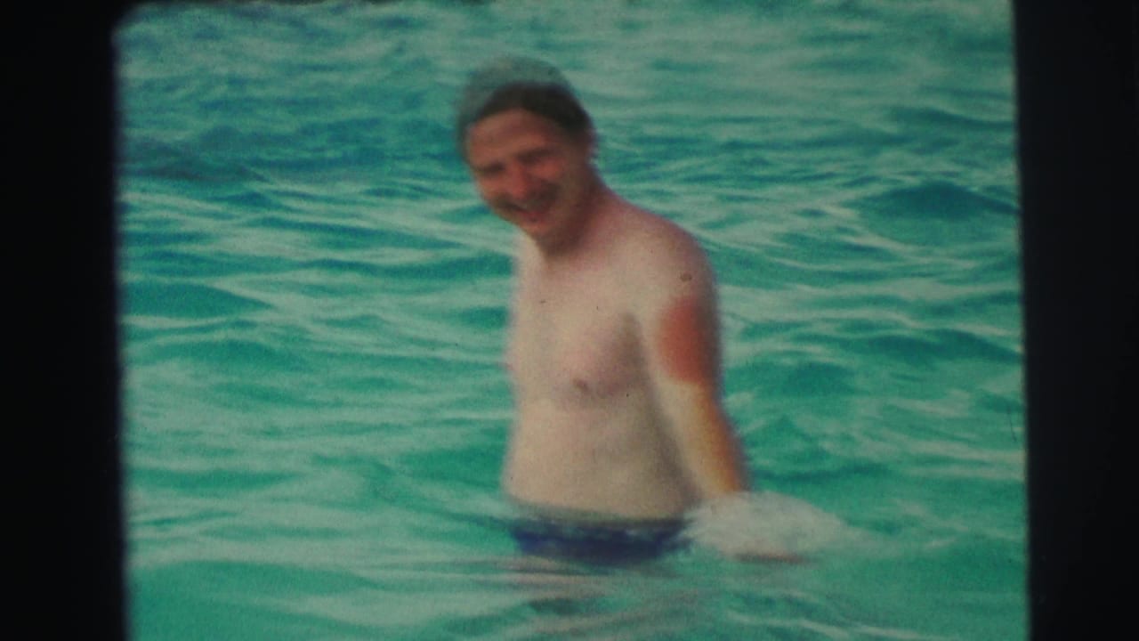 Adult man in a turquoise swimming pool, filmed in soft-focus 8mm style with Yellowstone, Wyoming supplied by metadata.