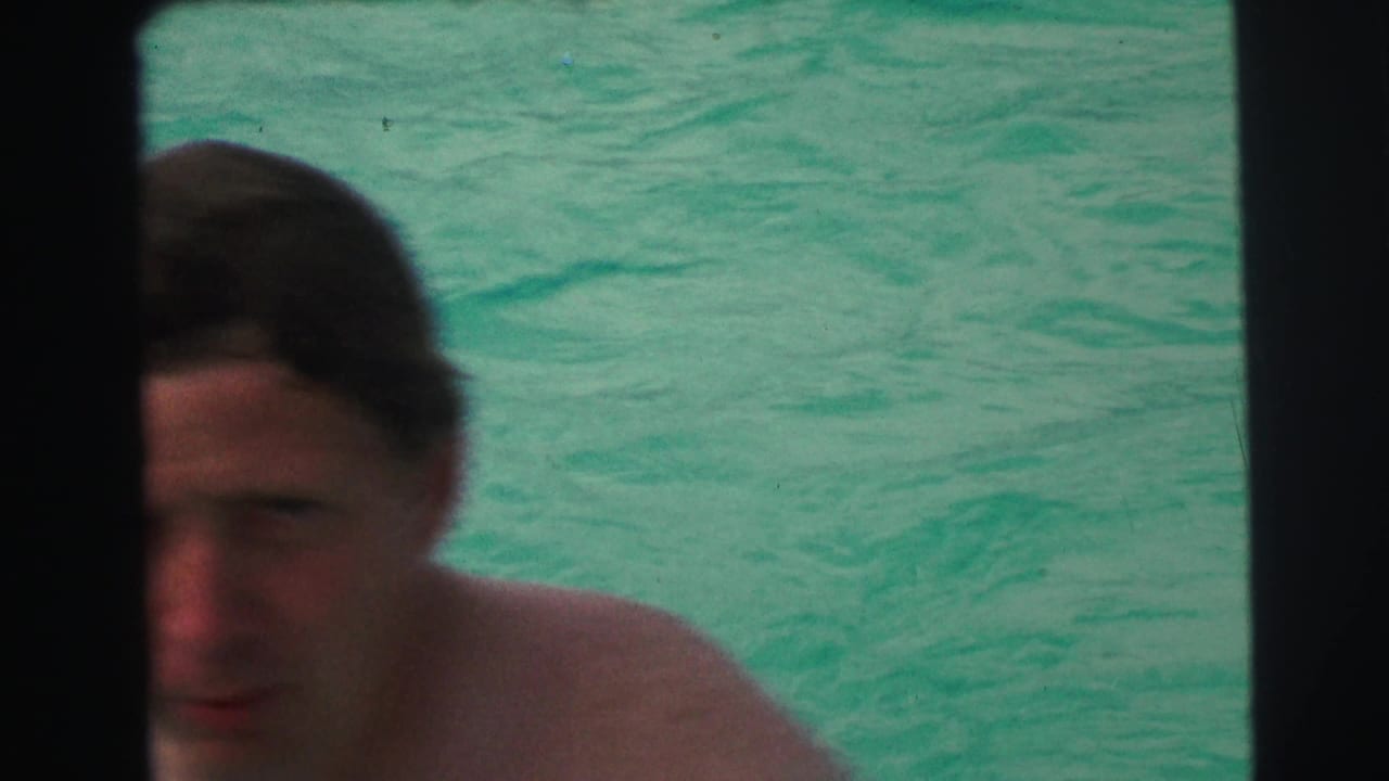 Close, partly obscured view of an adult swimmer in turquoise pool water, with dark contact-sheet borders crossing the frame.