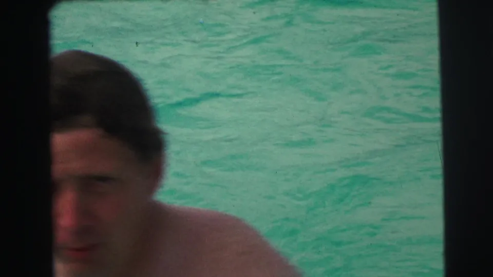 Close, partly obscured view of an adult swimmer in turquoise pool water, with dark contact-sheet borders crossing the frame.