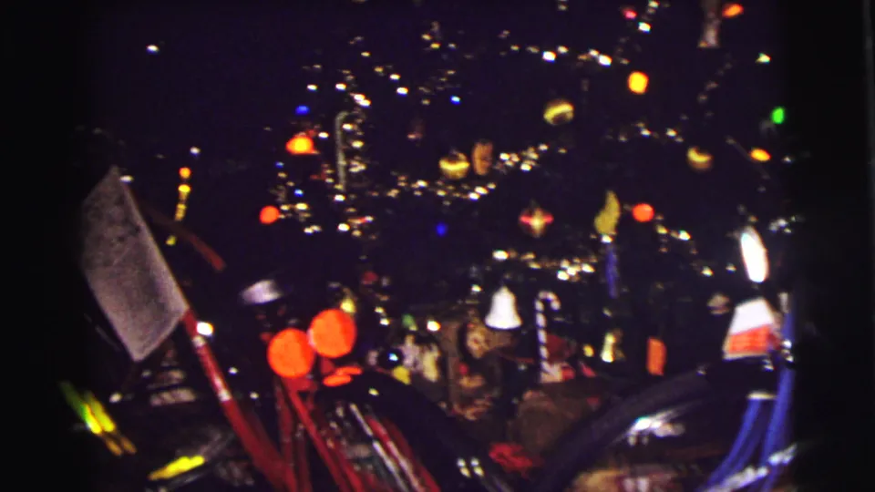 1972 East Lansing Christmas tree view with colorful bulbs, tinsel, ornaments, and bicycles partly visible in the foreground.