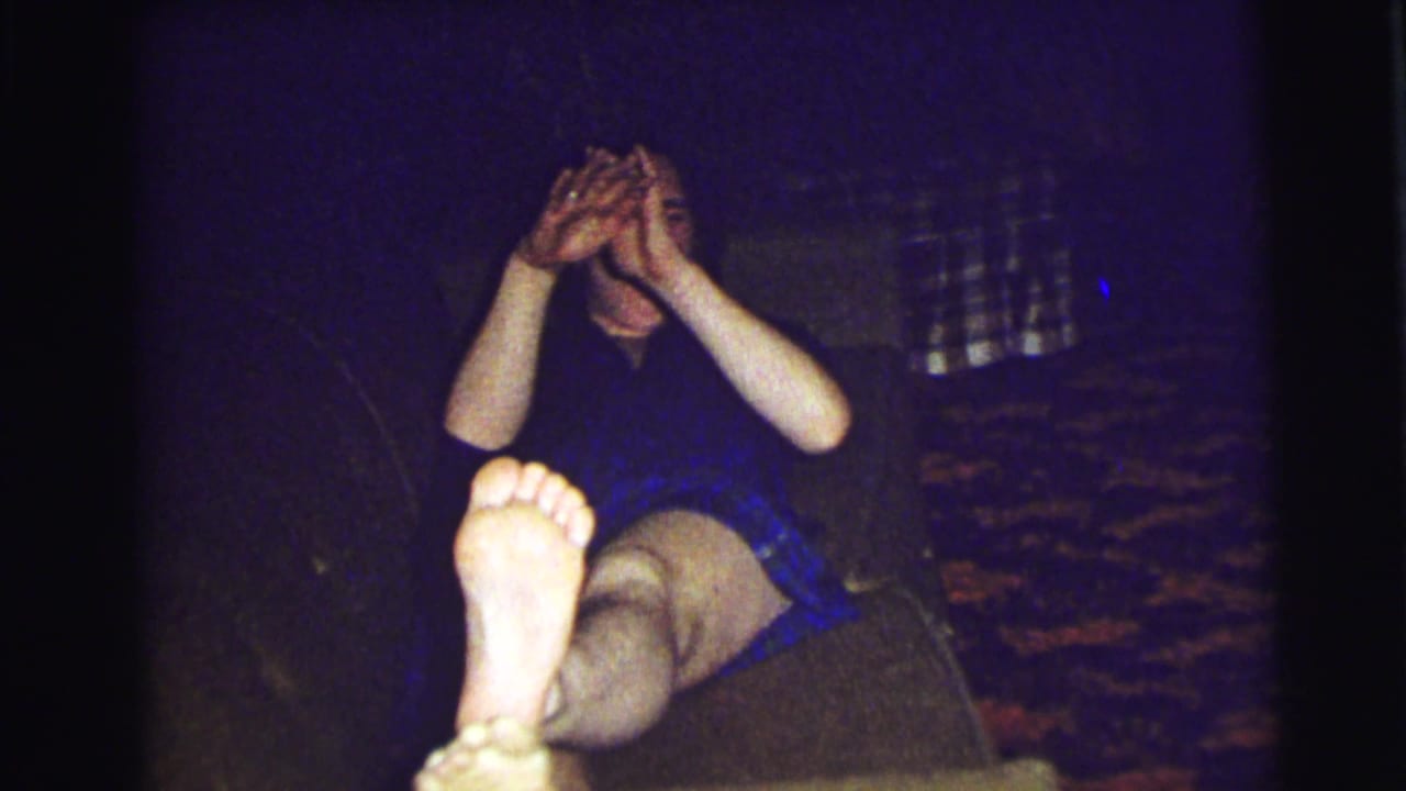 Man reclining on a dark couch with bare foot near the camera.
