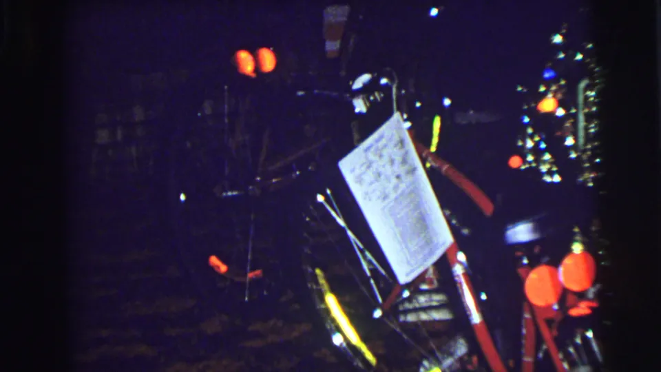 Final East Lansing frame shifts to a dark nighttime scene with bicycle-like shapes, small glowing lights, and a white paper or sign.