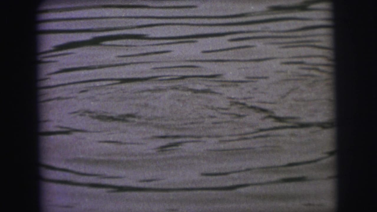 Rippling lake water fills the frame with dark film borders.