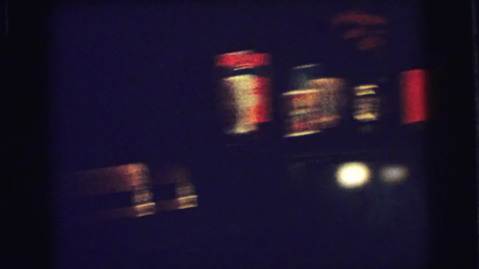 Blurred handheld view of a dark room with small bright lights or decorations in the 1973 home-movie clip.