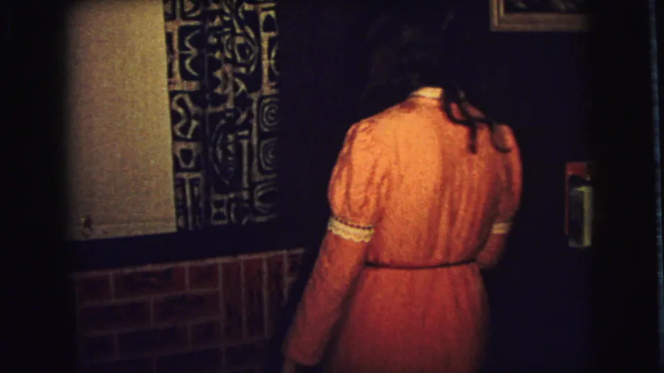 The young woman in the pink dress turns away near the fireplace in the 1973 Superior, Wisconsin home interior.