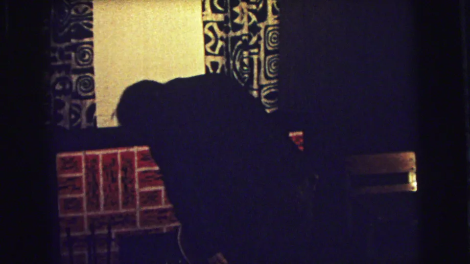 1973 Superior, Wisconsin home interior with a child bending near the brick fireplace or mantle area beneath patterned curtains.