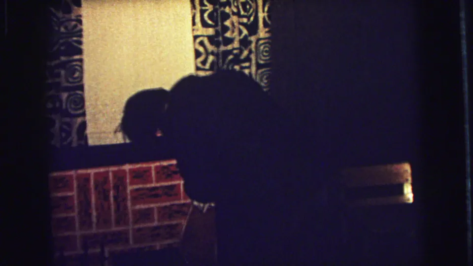 1973 home-movie frame showing the child near the fireplace in a private Superior, Wisconsin interior after reaching for the stocking.