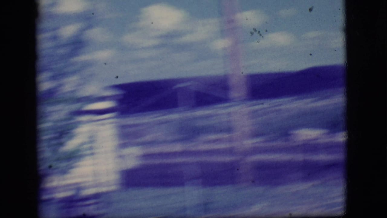 Blurred view of a pale house and low hills seen through 8mm film motion.