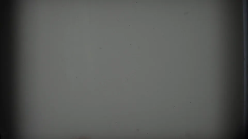 A nearly blank 8mm transition frame with gate edges and light dust before the home-movie scene begins.