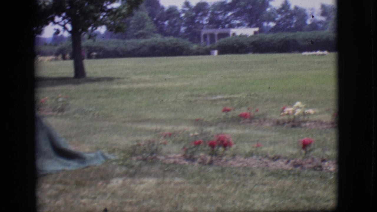 Des Moines cemetery grounds in 1966 with flower beds, lawn, trees, and small distant structures.