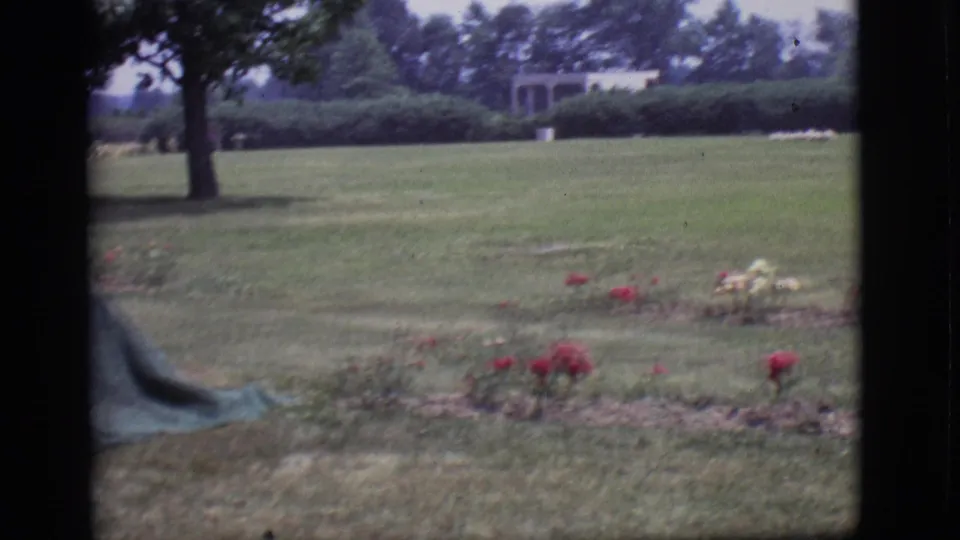 Des Moines cemetery grounds in 1966 with flower beds, lawn, trees, and small distant structures.