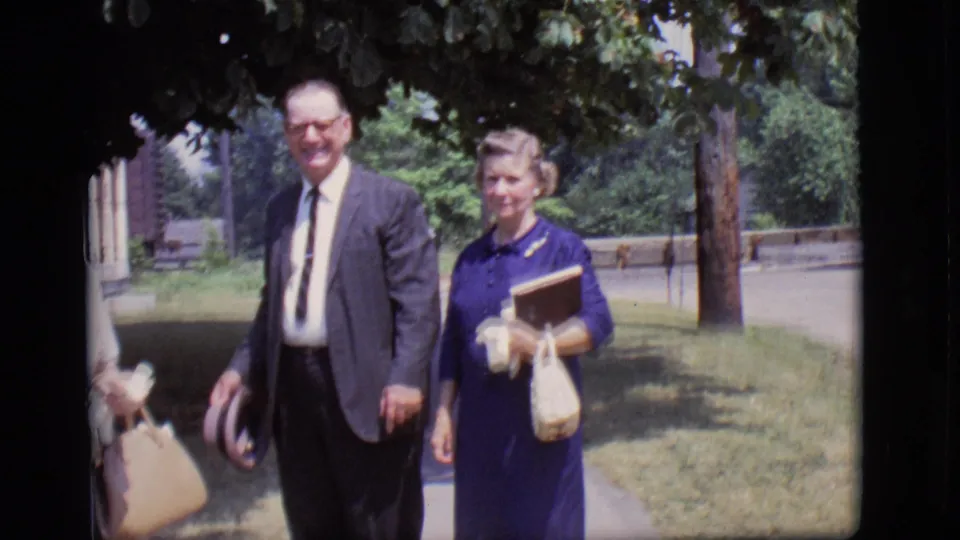 The final frame shows the suited man and woman in blue walking side by side in the 1966 Des Moines sidewalk scene, with another woman partly visible.