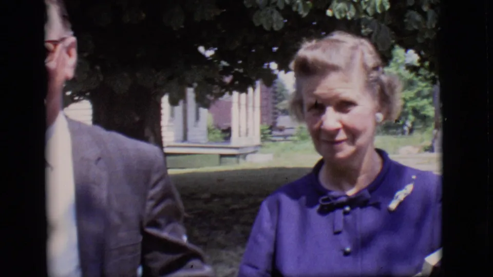The final frame centers the woman in a purple dress outdoors in Des Moines, with the suited man partly visible beside her.