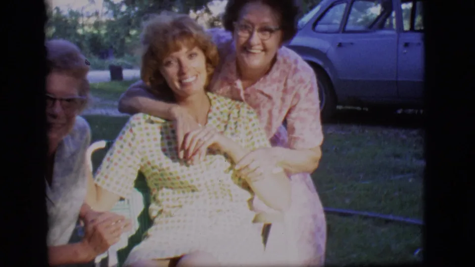 Three adult women in a Des Moines backyard smile and lean close together in 1966 home-movie footage.