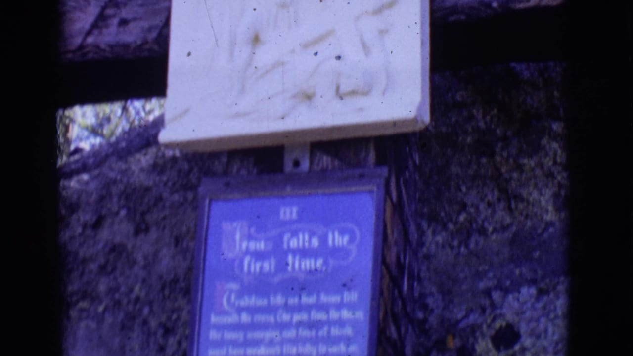 Blue religious plaque below a pale wooden element on a rough stone wall.