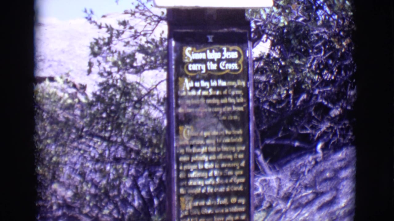 Way of the Cross sign about Simon helping Jesus carry the Cross beside trees.