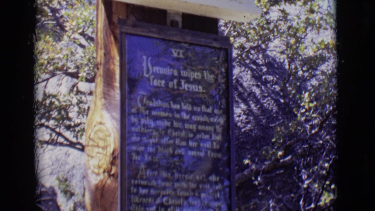 1965 San Luis, Colorado 8mm frame showing a blue Station VI plaque for Veronica wiping the face of Jesus on an outdoor marker.