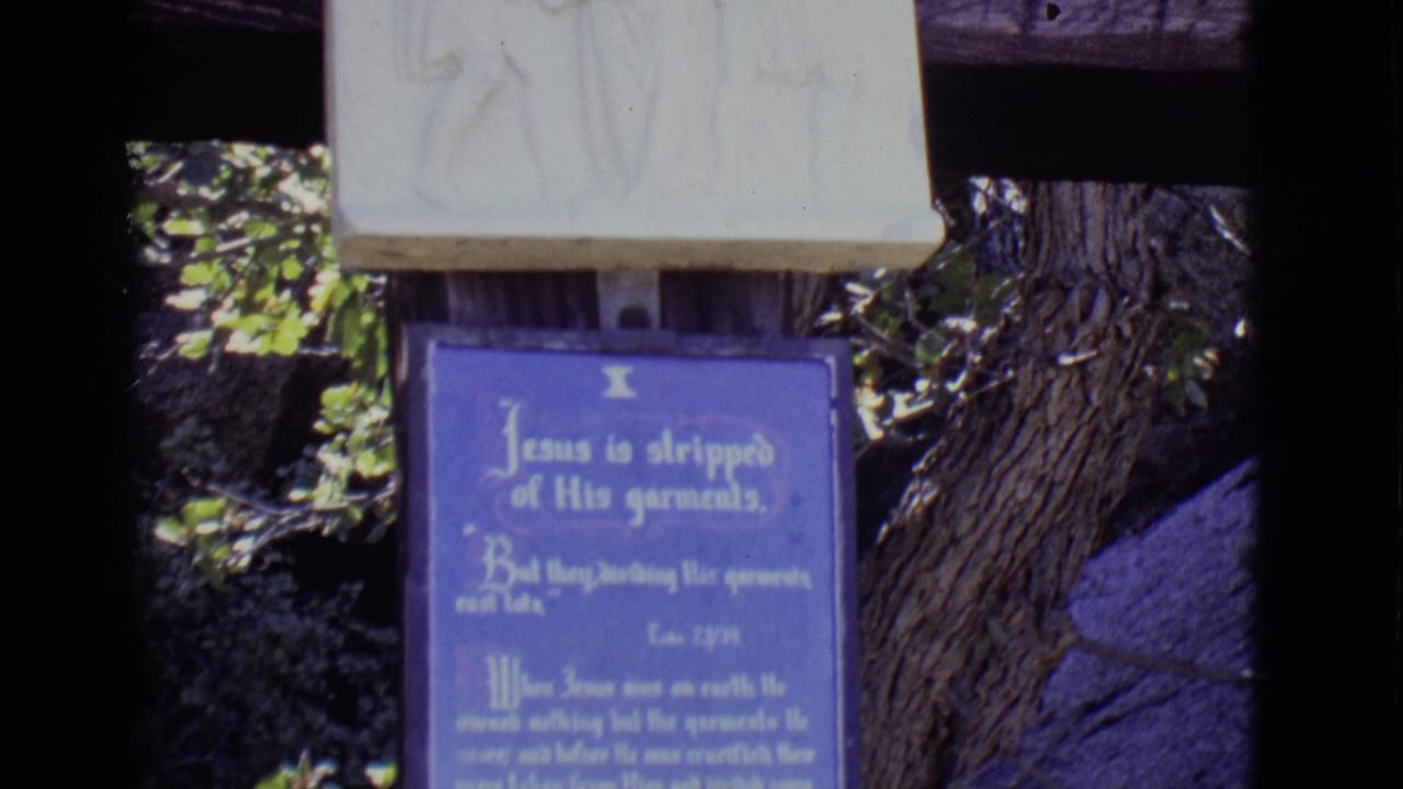 Blue plaque beneath a pale stone relief at an outdoor religious station.