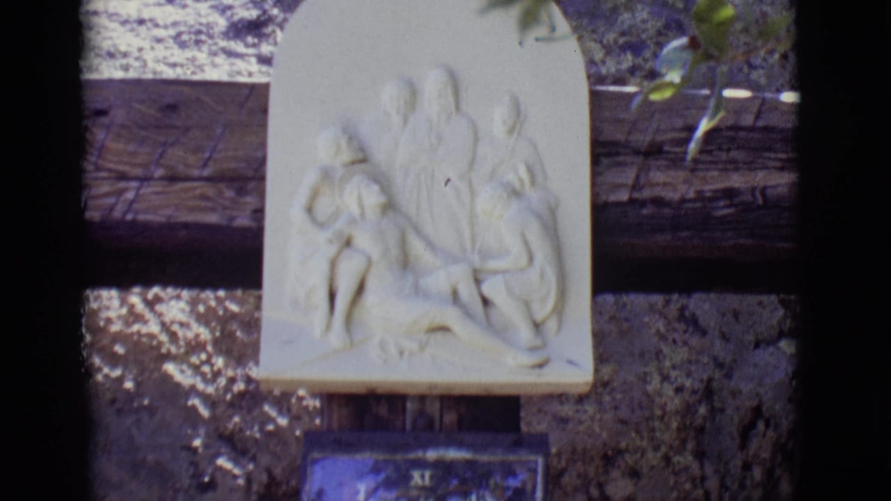 White relief sculpture above a blue Station XI plaque on a stone wall.