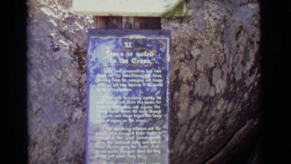Close view of the blue Station XI plaque reading as part of an outdoor Stations of the Cross display in San Luis, Colorado.
