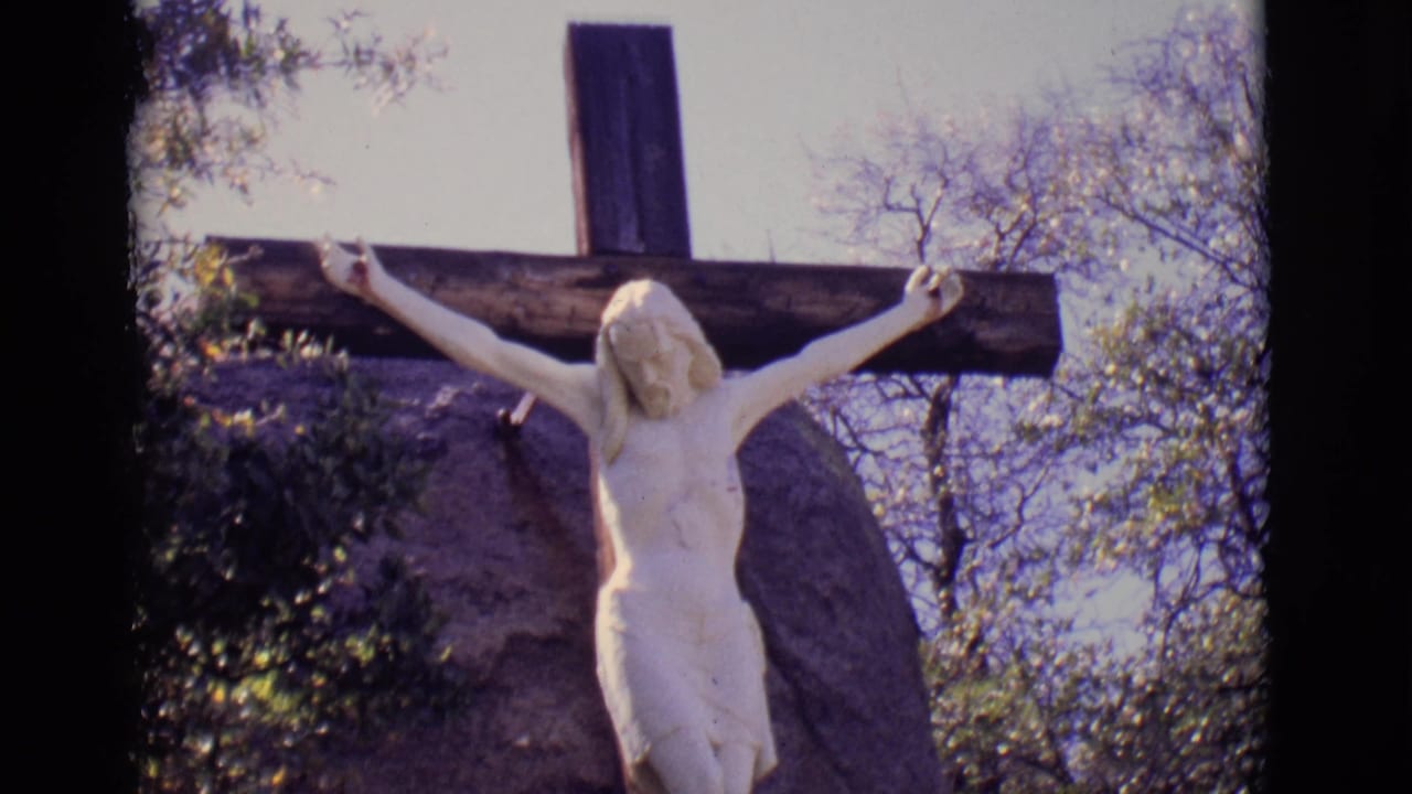 1965 San Luis, Colorado frame of the crucifixion statue, with the cross and white figure set among rocks, brush, and leafless branches.
