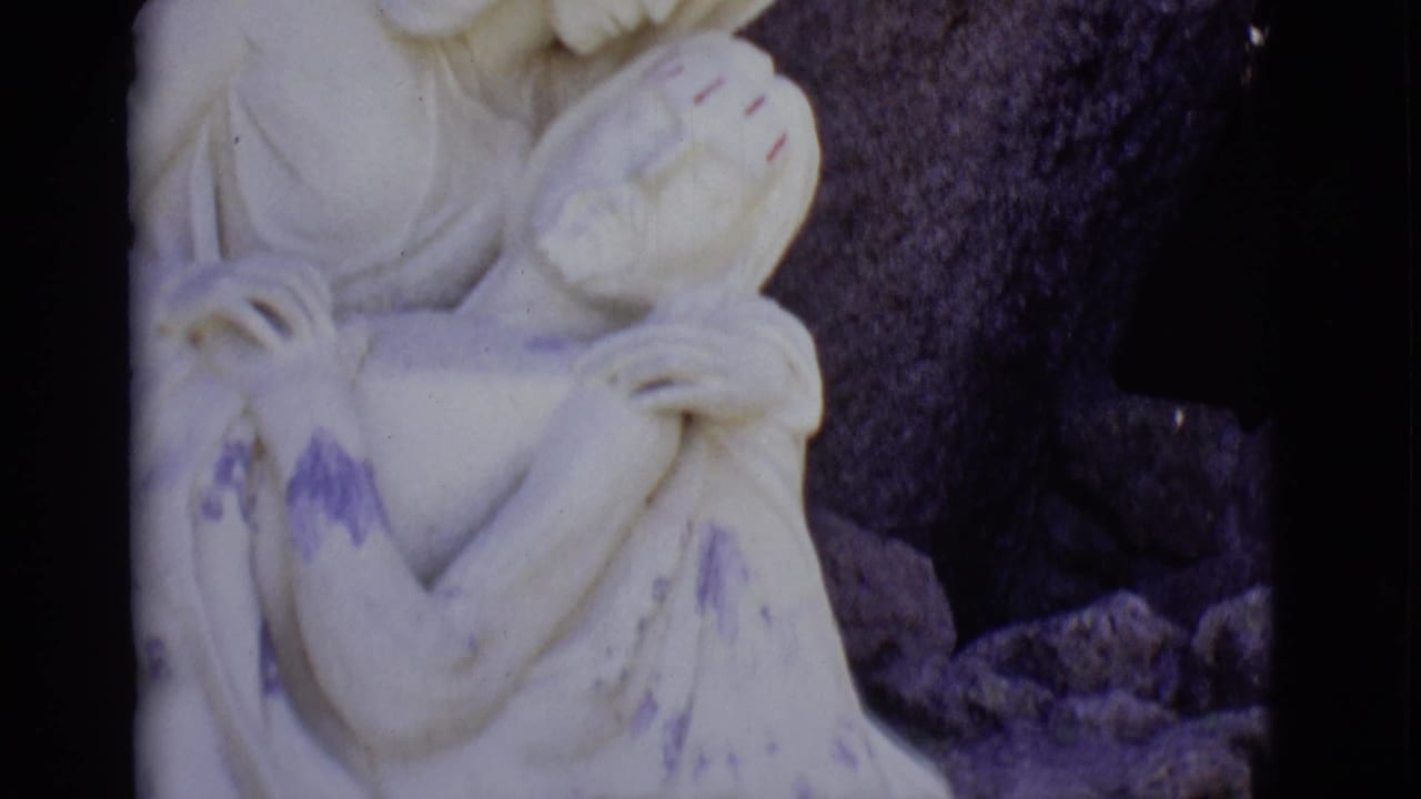 Pieta sculpture with Mary holding Jesus against dark stone.