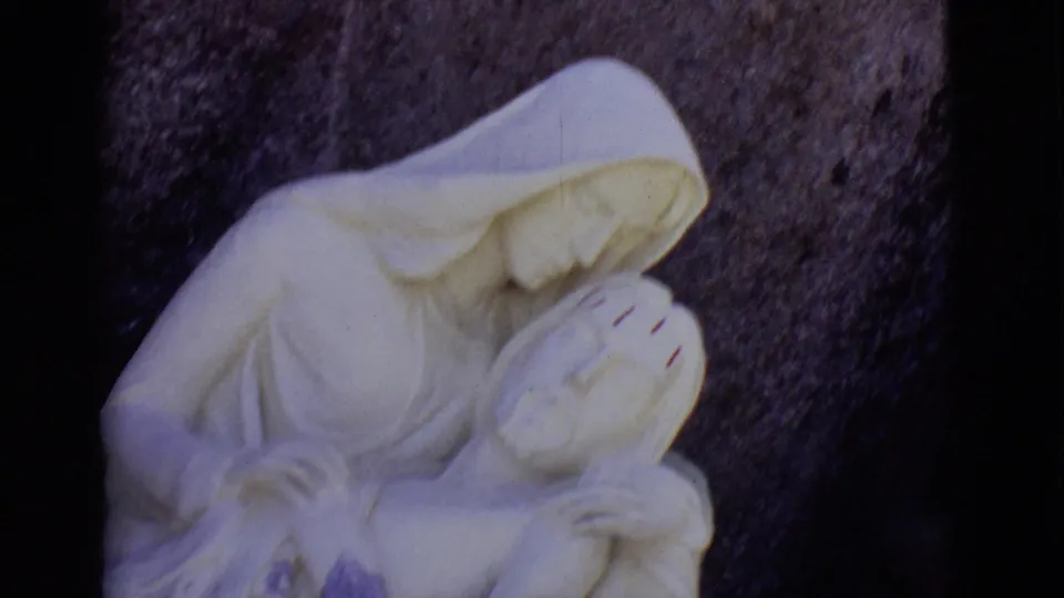 1965 8mm close view in San Luis, Colorado, with Mary leaning over Jesus in the Pieta sculpture and the frame partly cropped.